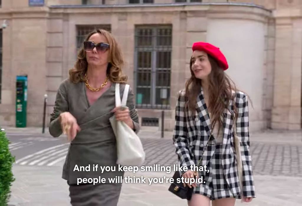 Emily (Lily Collins) in her red beret with her bitchy boss Sylvie (Philippine Leroy-Beaulieu, who is objecting to Emily’s constant smile.