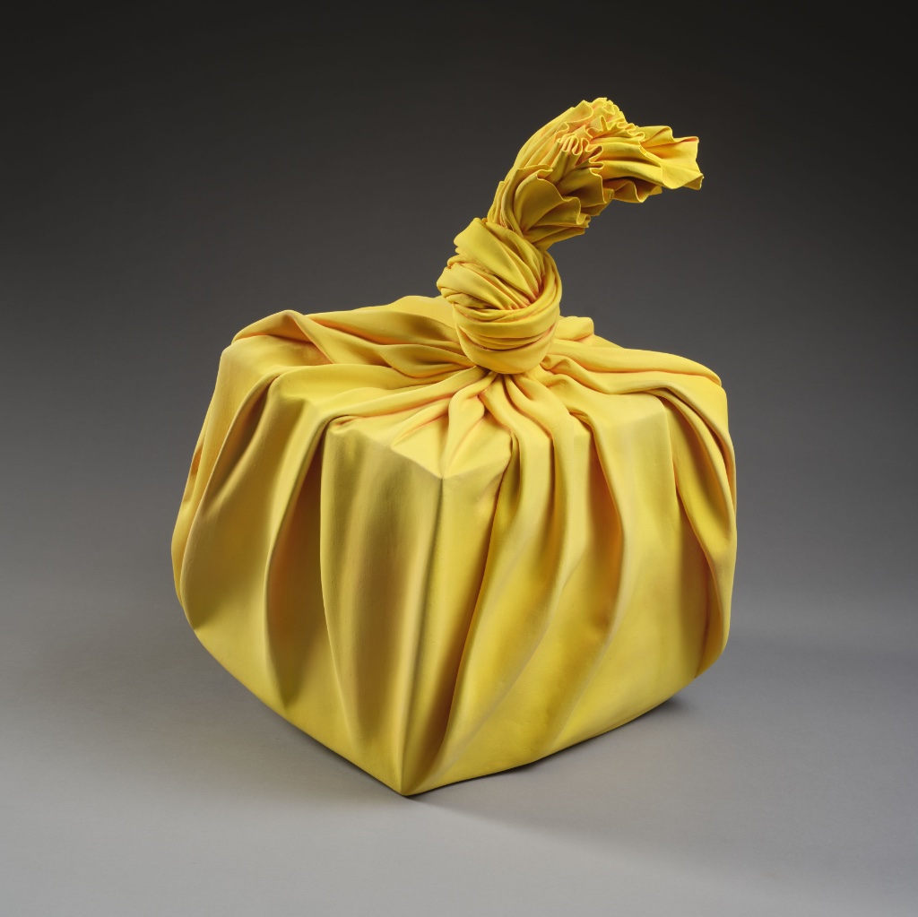 Yellow sculpture in the shape of a furoshiki tied around a cube (2020), by Tanaka Yu. © RMN-Grand Palais (MNAAG, Paris)/Thierry Ollivier